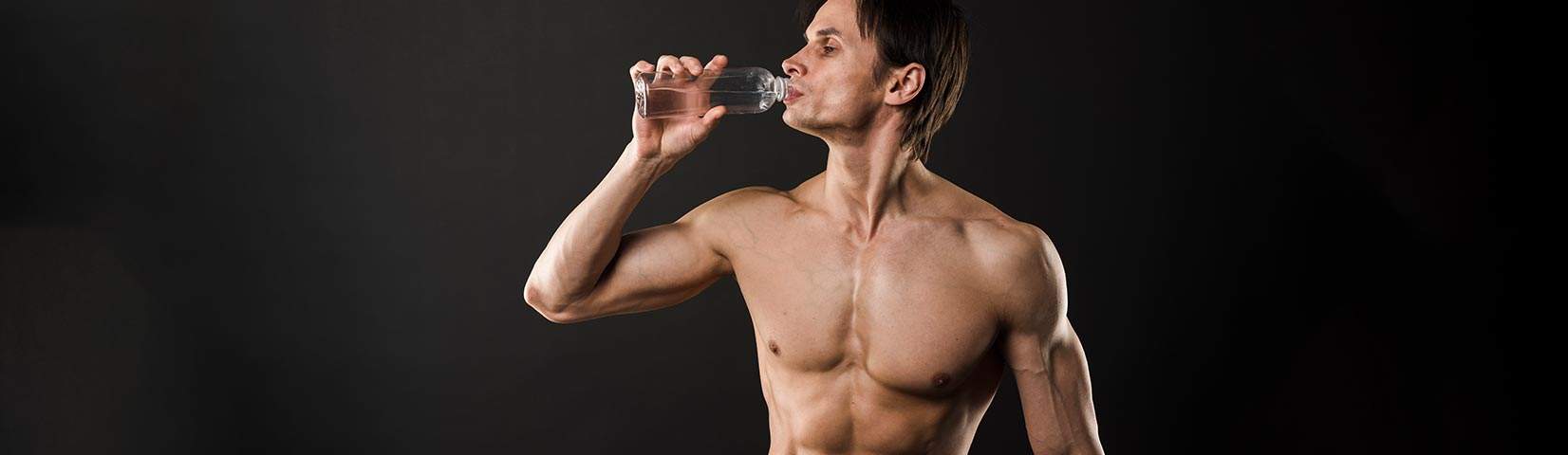 shirtless athletic man drinking from waterr bottle